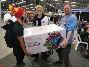 Two Supa-Fans holding a large white box containing a Marvel AndaSeat Gaming Chair.